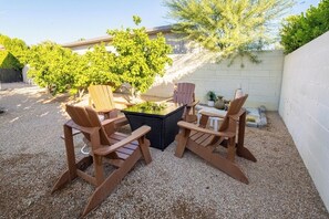 A patio with Adirondack chairs, a glass-top table, and a small fire pit. - Beautiful Palm Springs Home 3 bedrooms with Large Private Yard,Pool and Hot Tub (Palm Springs)
