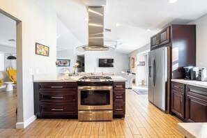 Una cocina moderna con gabinetes de madera oscura, electrodomésticos de acero inoxidable y una isla central.