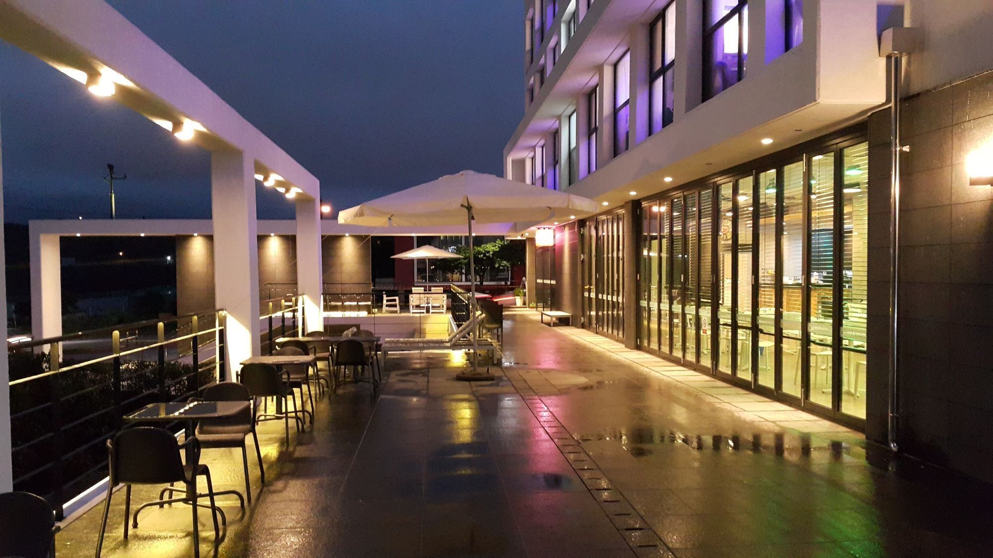 An outdoor patio area with tables and chairs, a covered seating area, and a view of the building's exterior.