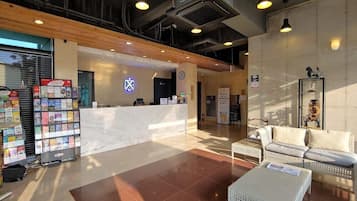 A lobby with a reception desk, seating area, and a display of magazines.