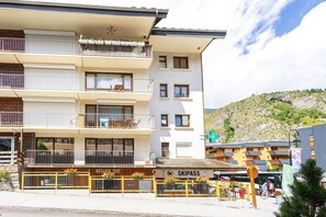 Ett hotell med flera våningar och balkonger, en synlig restaurang som heter ”ACCUEIL DOMAINE SUIVABLE” och en skylt för ”SKIPASS”.
