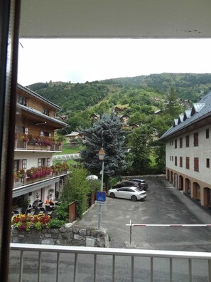 A view of a street with buildings, a parked car, and a sign indicating a pharmacy. - 100m from ski slopes, 1st floor, balcony, parking, tv, ski locker, 28m², Valloire (Valloire)