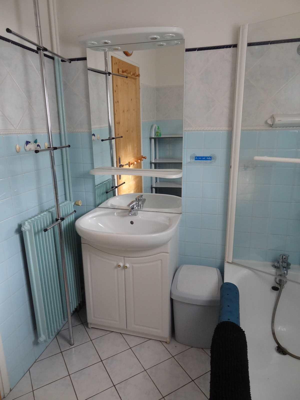 Ein Badezimmer mit weißem Waschbecken, Spiegel und Dusche.