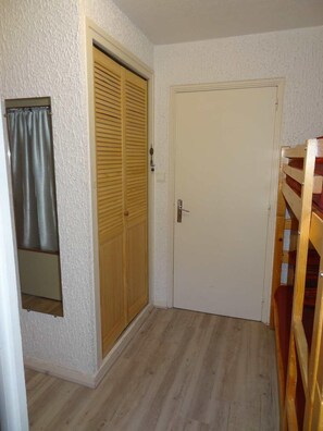 Une pièce avec une armoire en bois, une porte blanche et un miroir au mur.