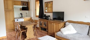 A compact living space with a kitchenette, wooden furniture, a flat-screen TV, and a sofa with a fluffy pillow. - 150m from ski slopes, Ground floor, balcony, tv, ski locker, 33m², Valloire (Valloire)