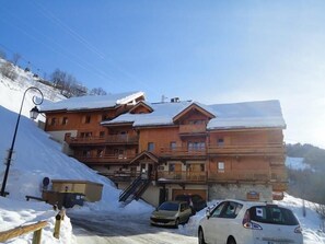 A multi-story wooden lodge with balconies, a staircase leading to the entrance, and a parking area with cars. - 150m from ski slopes, Ground floor, balcony, tv, ski locker, 33m², Valloire (Valloire)