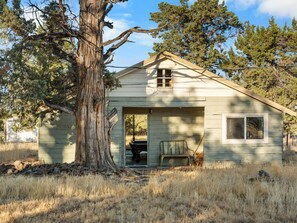 A small, single-story house with a front door, a window, and a porch. - Ranch Cabin w/ Game Room | Pool, Ping Pong, Arcade (Sisters)