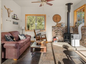 A cozy living room with a leather couch, a wooden coffee table, a fireplace, and a clock on the wall.