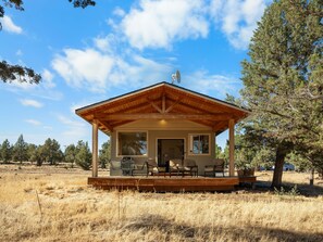 A cabin with a wooden deck, a satellite dish, and a view of the surrounding landscape.