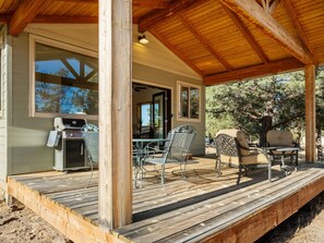 Une terrasse extérieure avec un barbecue, des chaises et une table.