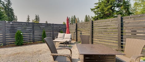 Un espace extérieur aménagé avec une table et des chaises, entouré d’une clôture en bois et recouvert de gravier.