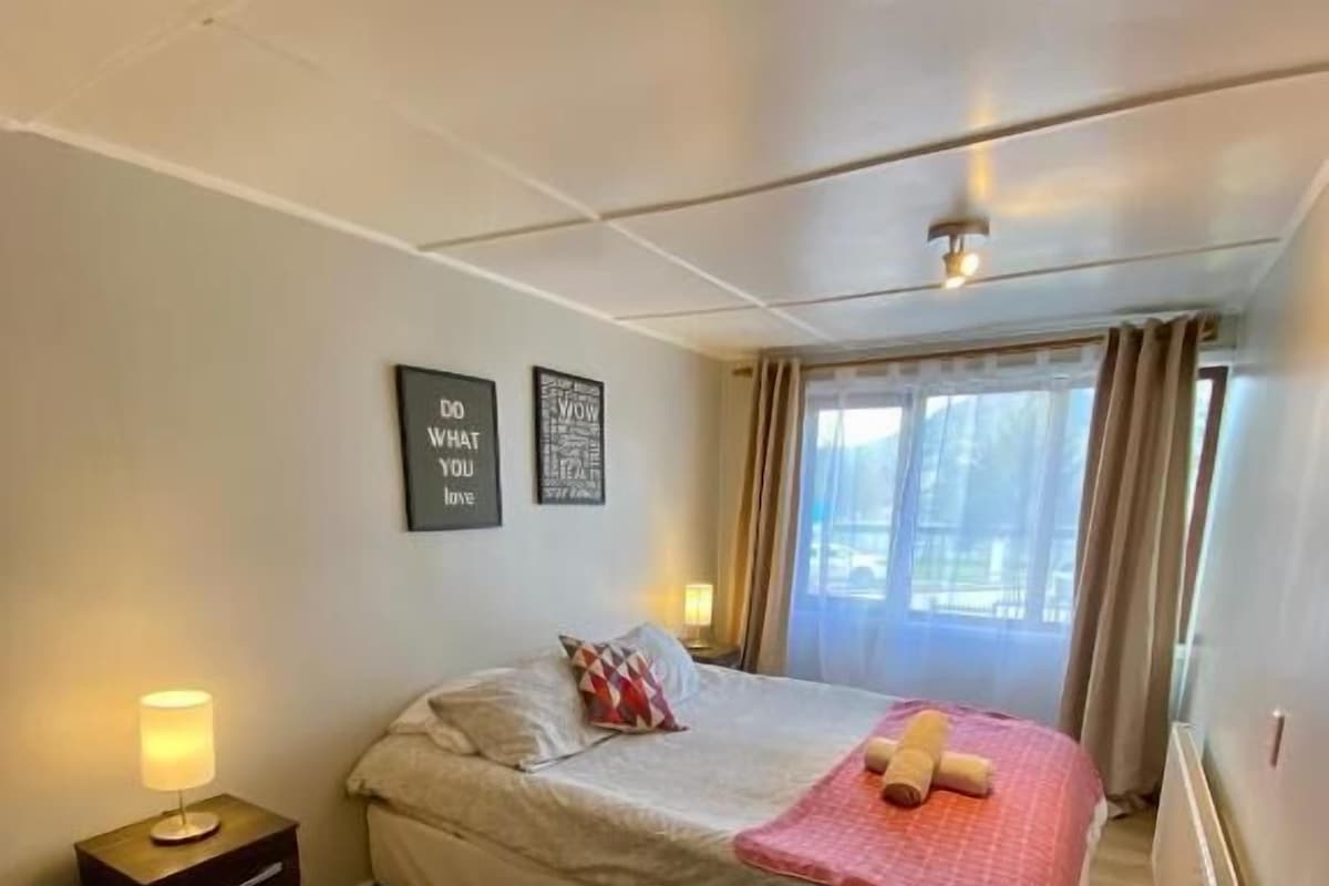 A bedroom with a bed, a nightstand, a window with curtains, and two wall-mounted motivational posters.