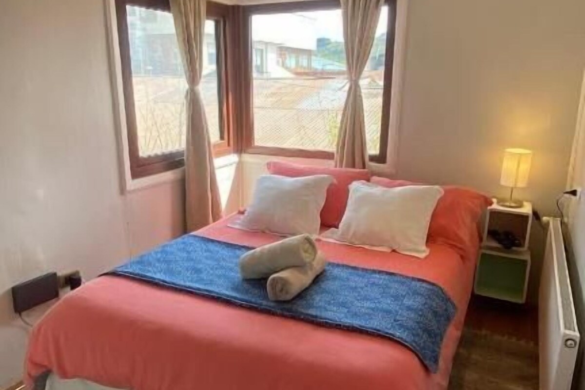 A bedroom with a bed, a nightstand, a lamp, and a view through the window.