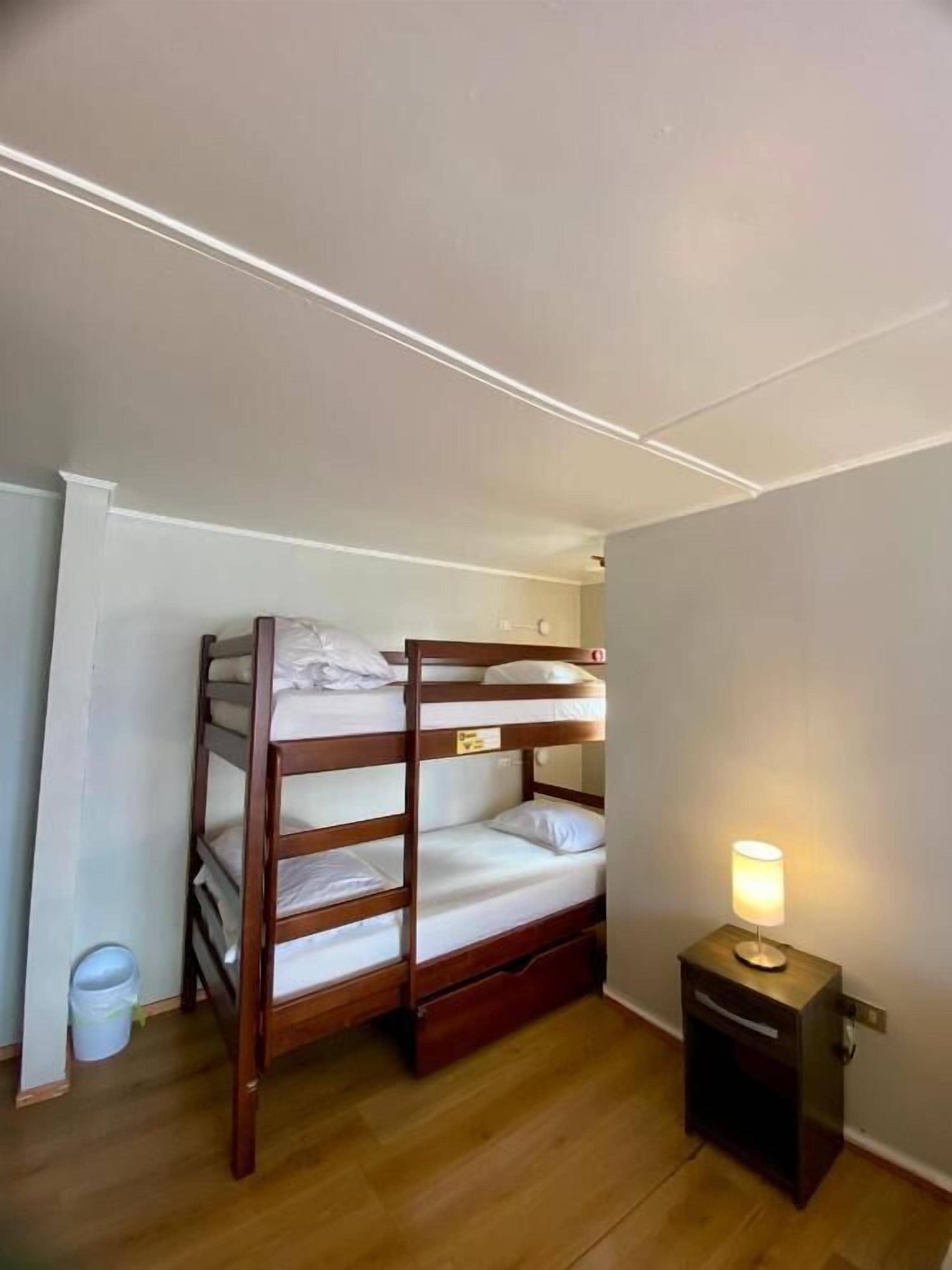 Ein Stockbett mit Nachttisch und Lampe, Holzboden und weiße Decke.