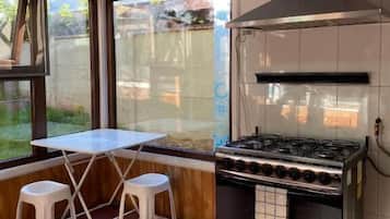 Una cocina con estufa a gas, campana extractora y ventana con vistas al exterior.