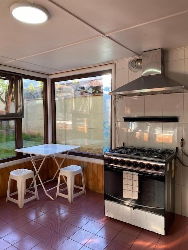 A kitchen with a gas stove, a range hood, and a window with a view of the outdoors.