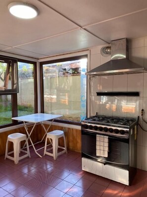 A kitchen with a gas stove, a range hood, and a window with a view of the outdoors.