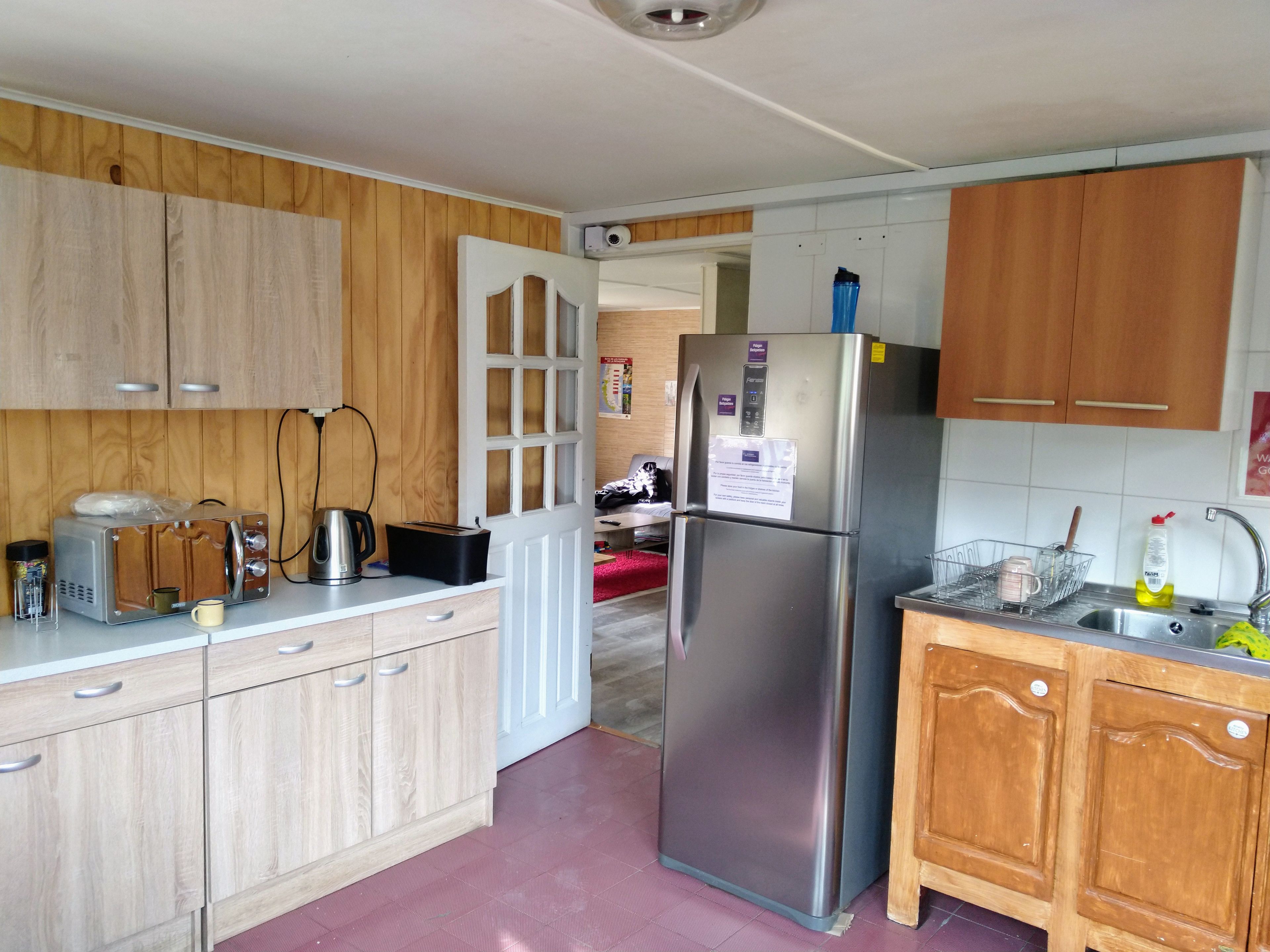 Eine Küche mit Holzausstattung, einem Edelstahlkühlschrank, einem Toaster und einem Wasserkocher.