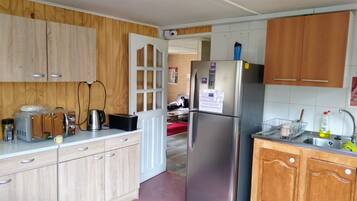 Eine Küche mit Holzausstattung, einem Edelstahlkühlschrank, einem Toaster und einem Wasserkocher.
