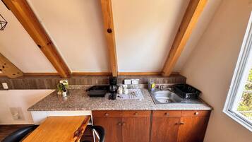 A compact kitchen with wooden beams, granite countertops, and a sink.