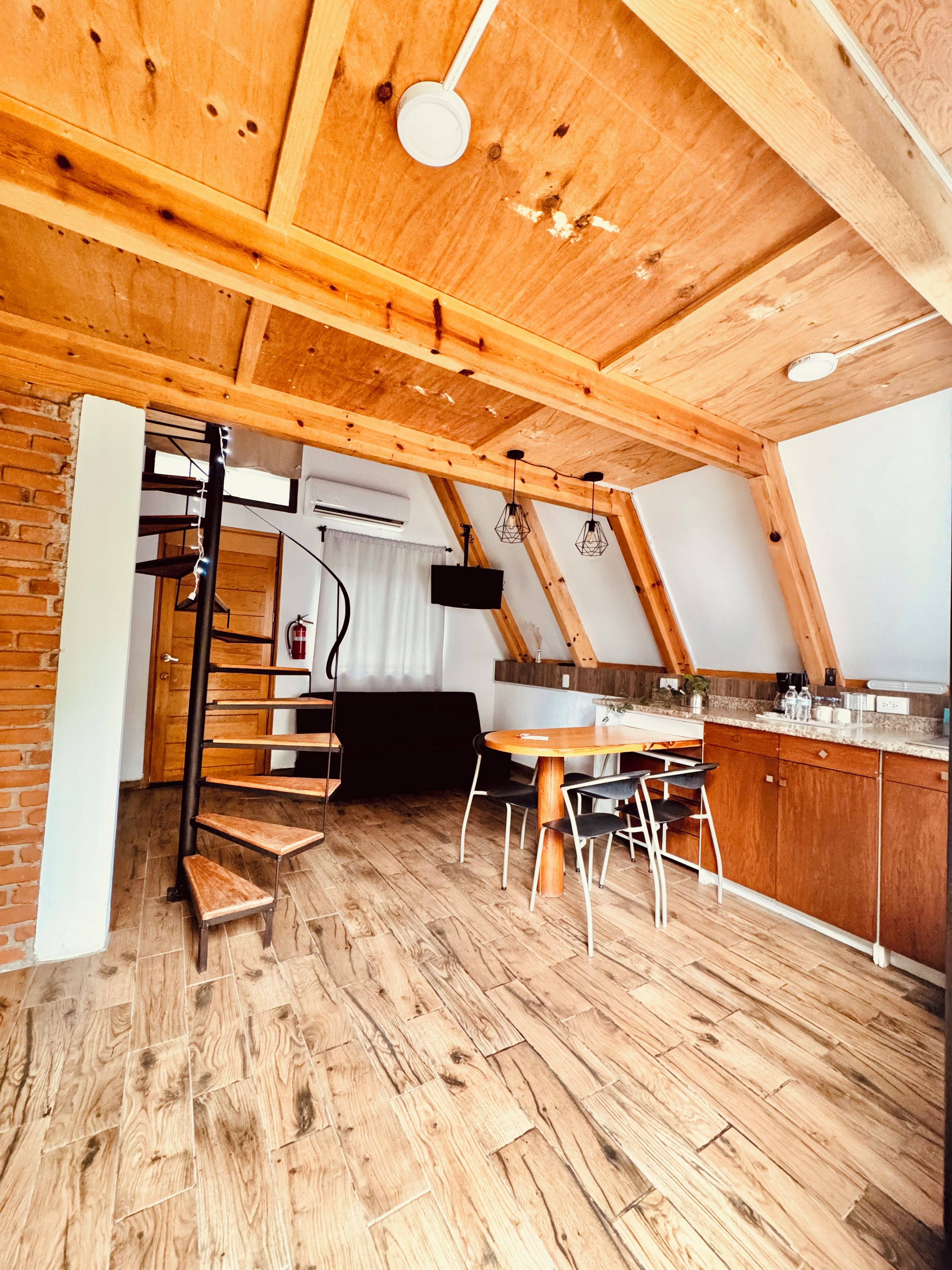 Eine moderne Küche mit Holzbalken, einem Essbereich mit rundem Tisch und einer Treppe, die in einen oberen Bereich führt.