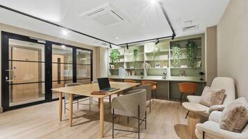Un espacio de oficina moderno con una mesa de madera, sillas, una computadora portátil y una estantería con plantas.
