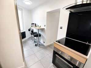 Una cocina moderna con estufa negra, encimera de madera y una zona con taburetes de bar.