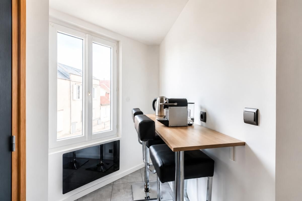 A compact kitchen with a window, a coffee machine, and two bar stools.