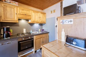 A compact kitchen with wooden cabinets, a gas stove, a built-in oven, a sink, and a microwave. - 300m from ski lifts, 3rd floor, balcony, parking, tv, ski locker, 59m², Valloire (Valloire)