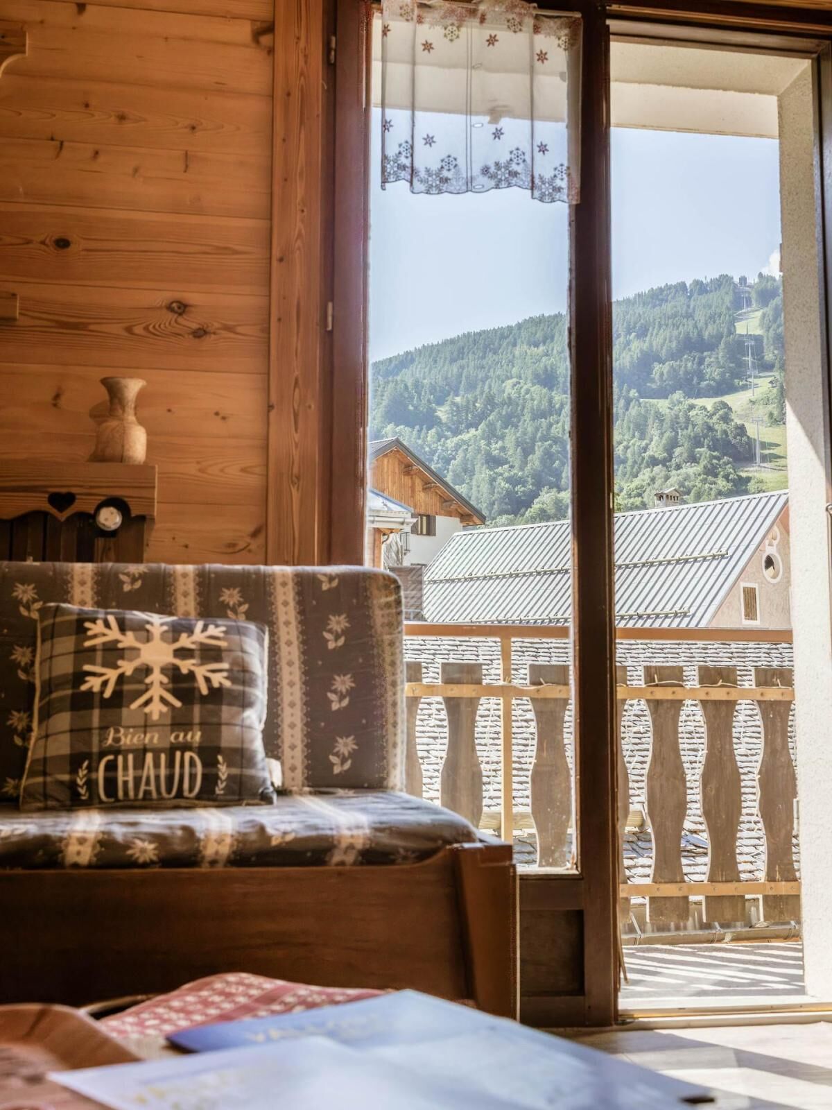 A wooden interior with a view of a mountainous landscape through a glass door.
