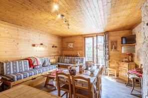 A wooden cabin interior with a dining area, sofa, and kitchen. - 300m from ski lifts, 3rd floor, balcony, parking, tv, ski locker, 59m², Valloire (Valloire)