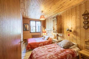 A wooden room with two beds, a window, a mirror, and a 'Bienvenue' sign. - 300m from ski lifts, 3rd floor, balcony, parking, tv, ski locker, 59m², Valloire (Valloire)