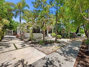 A residential property with a paved driveway, a house with a covered porch, and a variety of trees and shrubs. - Modern Design District Home 3 King Beds Near Wynwood (Miami)