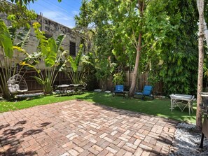 A backyard with a brick patio, green lawn, and outdoor furniture. - Modern Design District Home 3 King Beds Near Wynwood (Miami)