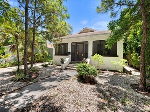 A single-story house with a front porch, a driveway, and a well-maintained garden with various plants and trees. - Modern Design District Home 3 King Beds Near Wynwood (Miami)