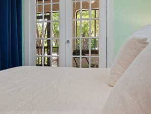 A bedroom with a bed, a window with a view of greenery, and a door with a view of a patio area. - Modern Design District Home 3 King Beds Near Wynwood (Miami)