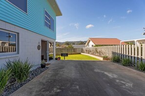 A residential property with a paved driveway, a wooden fence, and a sign indicating a private driveway. - Wharf Landing: The Studio (Coromandel)