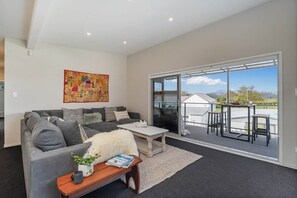 A modern living room with a grey sofa, a coffee table, and a large window.