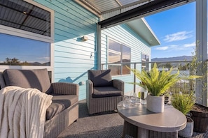 Ein Balkon mit Korbmöbeln, einem Tisch und Blumentöpfen.