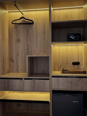 Un mueble de madera con estantes, una percha para colgar ropa y un electrodoméstico empotrado.