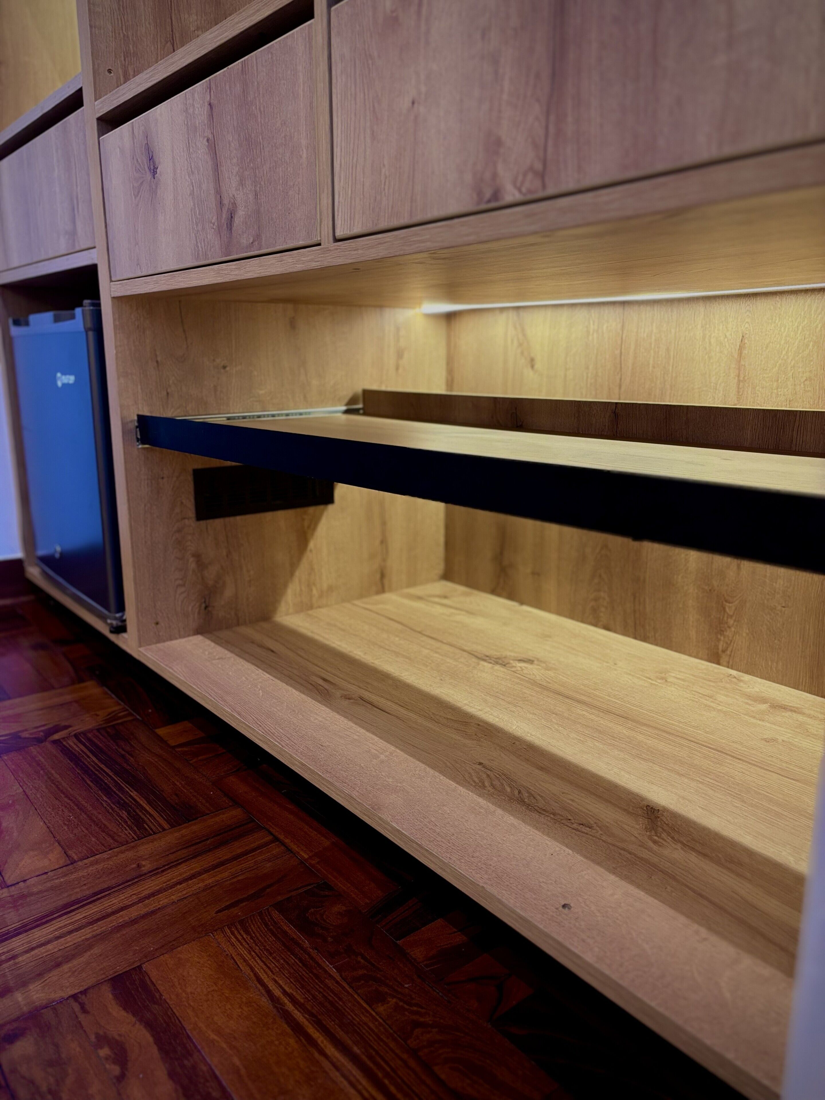 Un mueble de madera con varios compartimentos, un televisor de pantalla plana y piso de madera.