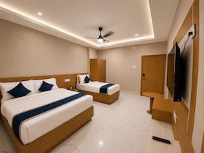 Habitación de hotel con dos camas, ventilador de techo, televisor y armario de madera.