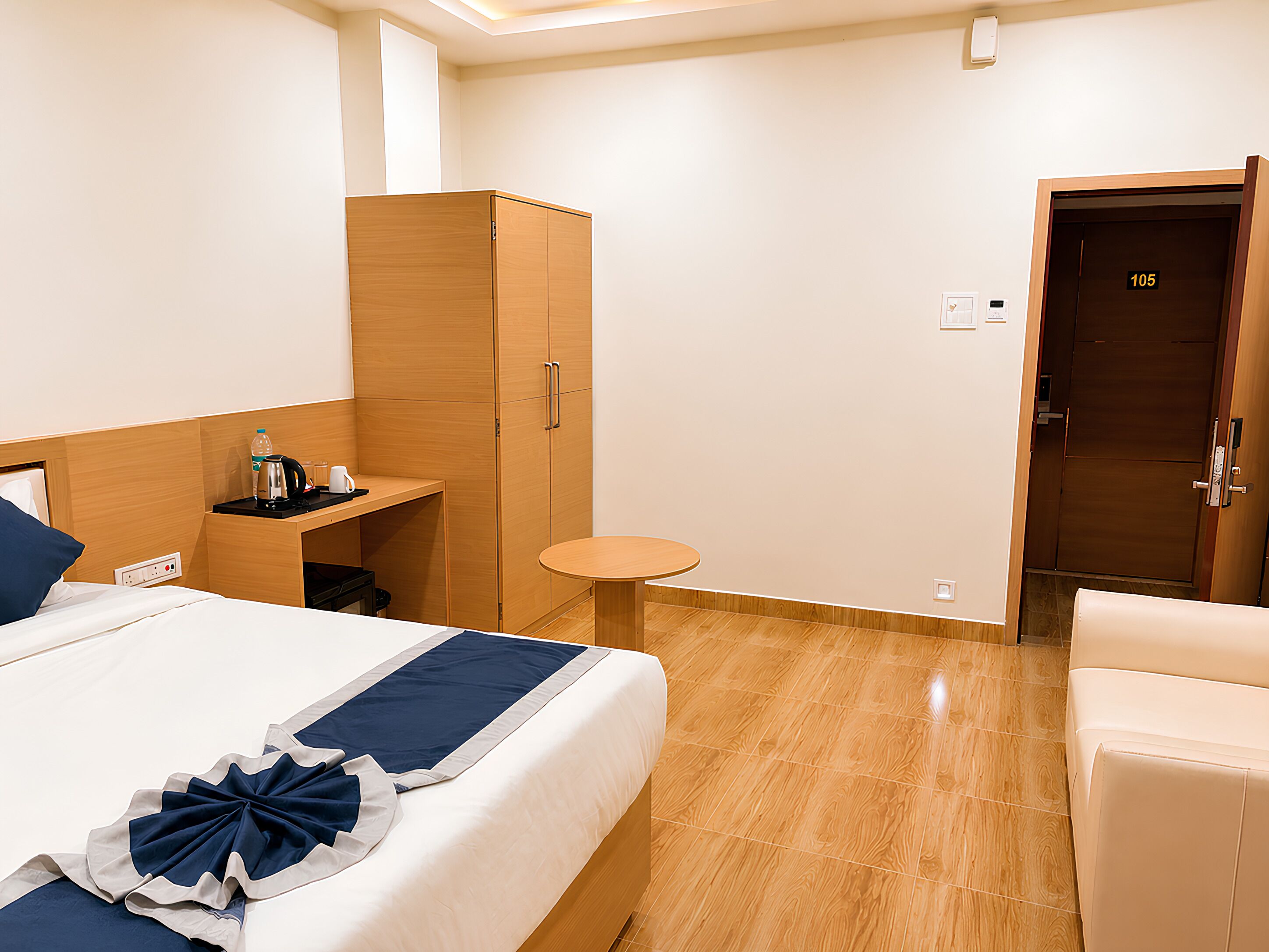 Ein Hotelzimmer mit einem Bett, einem kleinen Tisch, einem Kleiderschrank und einer Tür mit der Nummer 105.