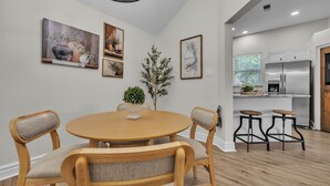 A dining area with a round wooden table, four chairs, and a potted plant.