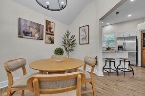 A dining area with a round wooden table, four chairs, and a potted plant.
