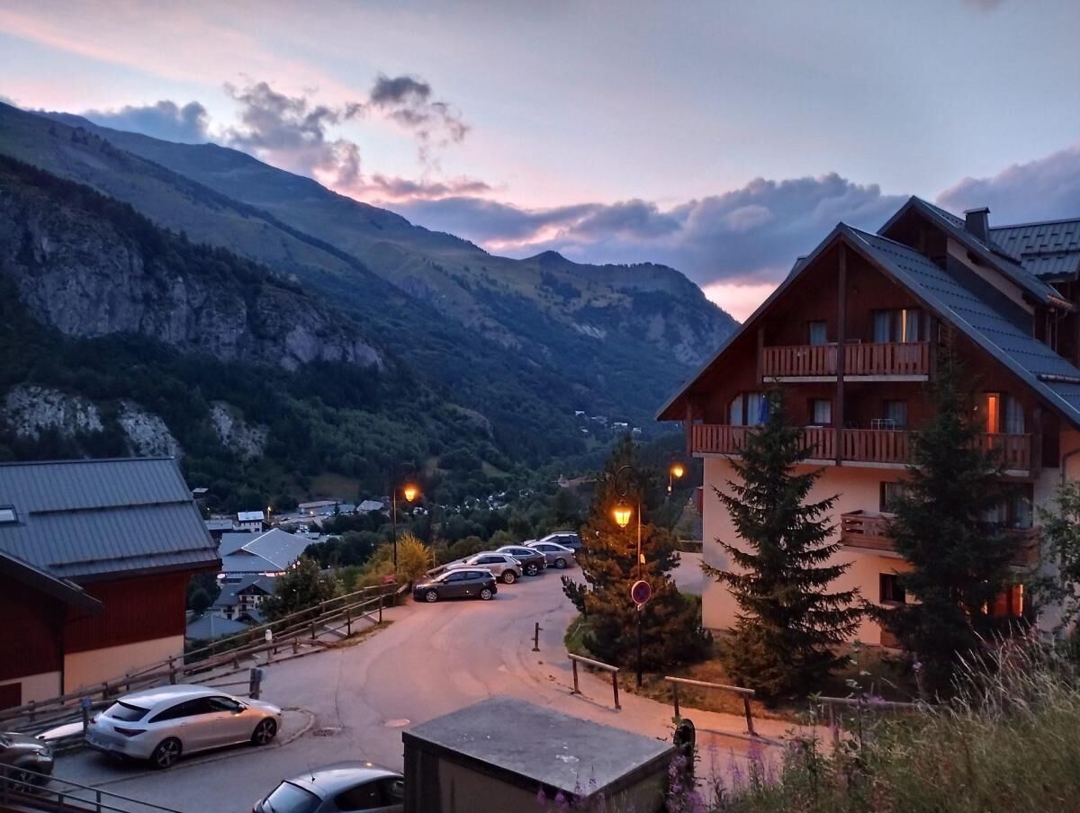 Une station de montagne dotée d’un parking, d’un bâtiment avec balcon et offrant une vue sur les montagnes.