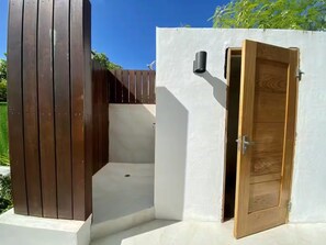 Une porte en bois donne sur une pièce aux murs blancs, dotée d’une petite fenêtre et d’une sonnette.