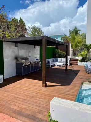 Un espace extérieur abrité comprenant un barbecue, des sièges et une piscine.