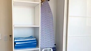Ein weißer Kleiderschrank mit mehreren Einlegeböden, einer Kleiderstange und einer kleinen schwarzen Box auf der untersten Ablage.