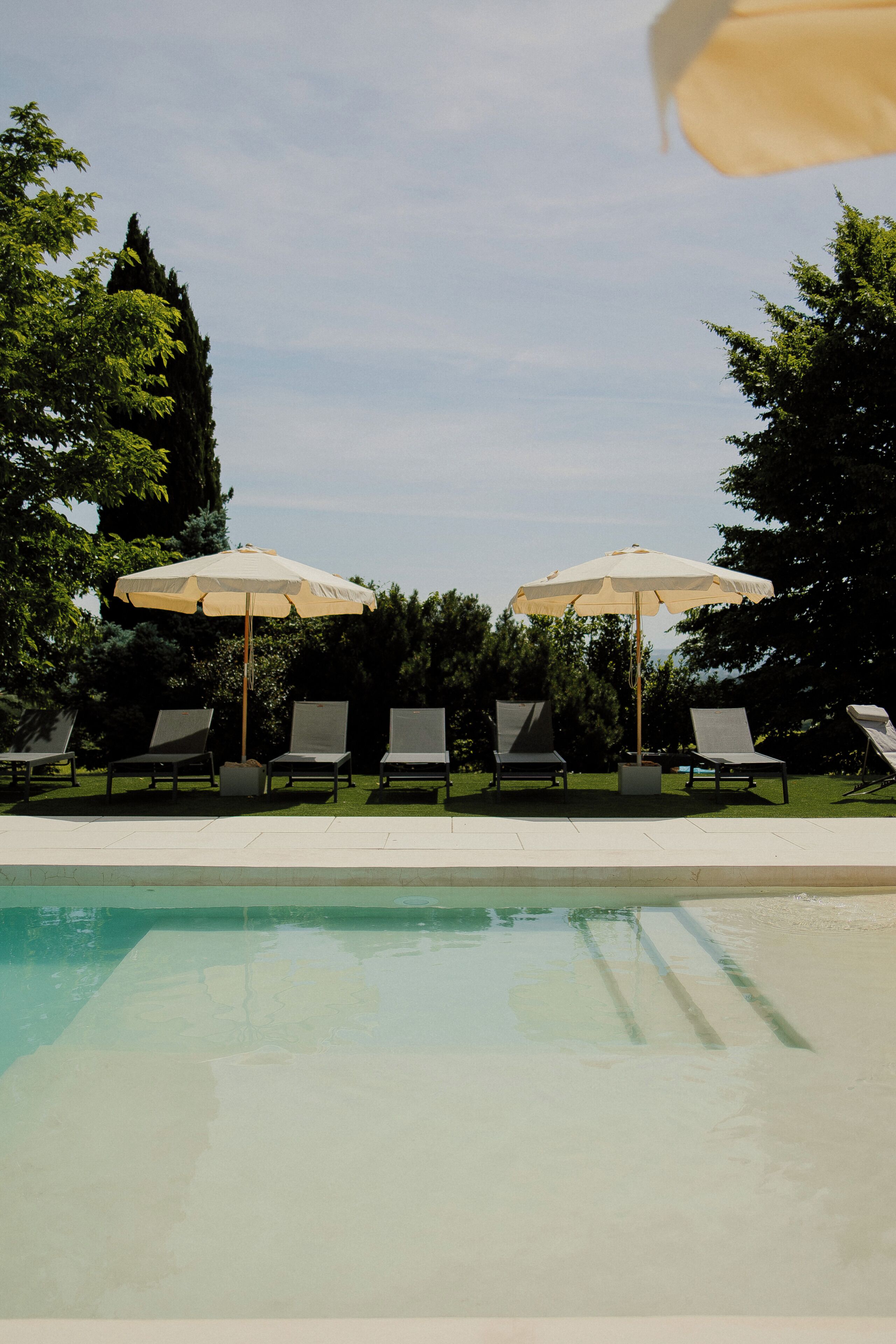 Une piscine avec des chaises longues et des parasols.